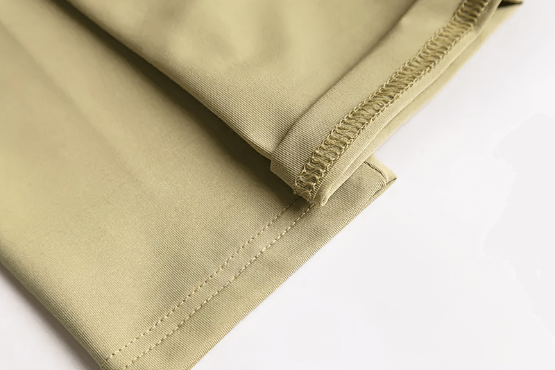 Close-up of a men's elastic breathable running T-shirt hem, showcasing detailed stitching on a light khaki fabric.